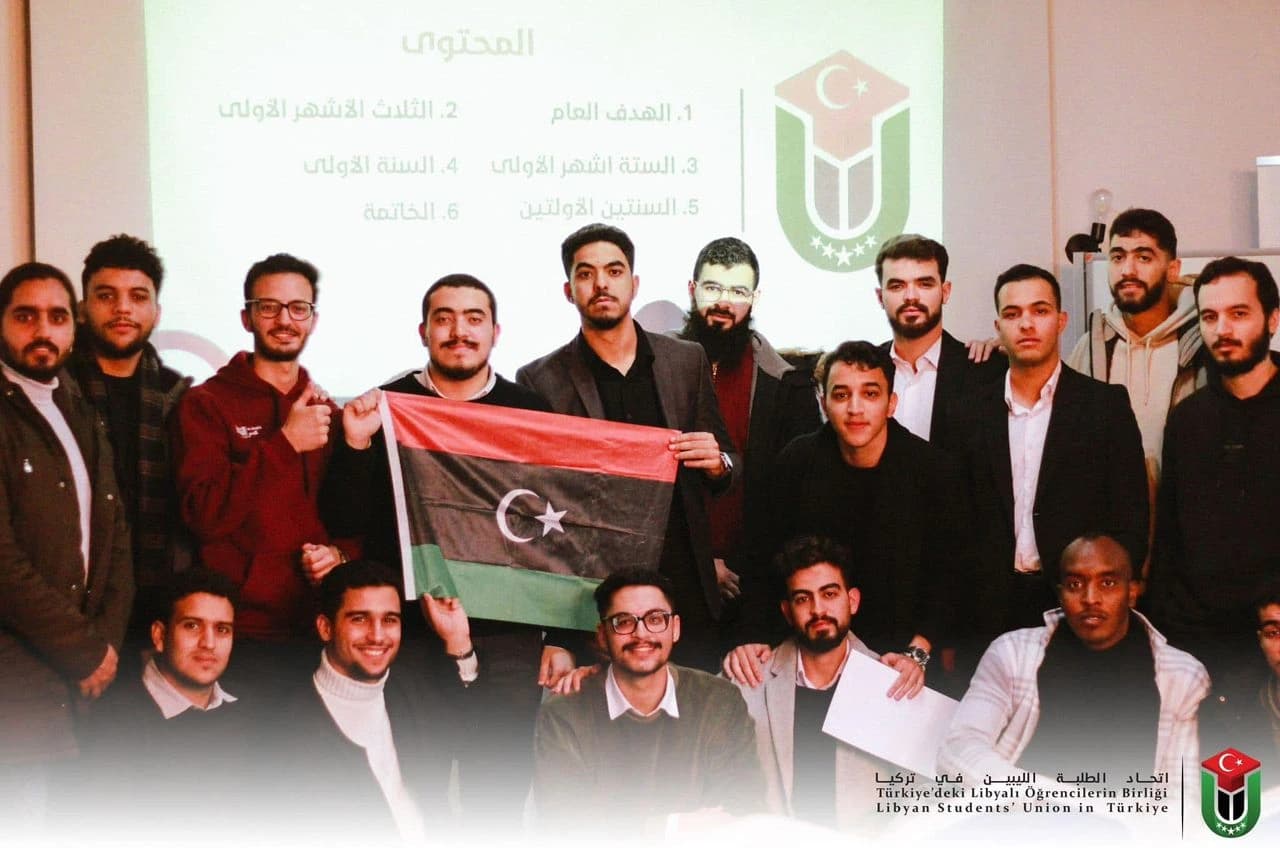 أعضاء اتحاد الطلبة الليبيين في تركيا يحملون العلم الليبي أمام شعار الاتحاد خلال إحدى الفعاليات